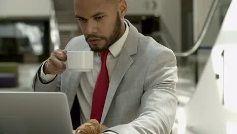 Handsome-bearded-businessman-working-during-coffee-break